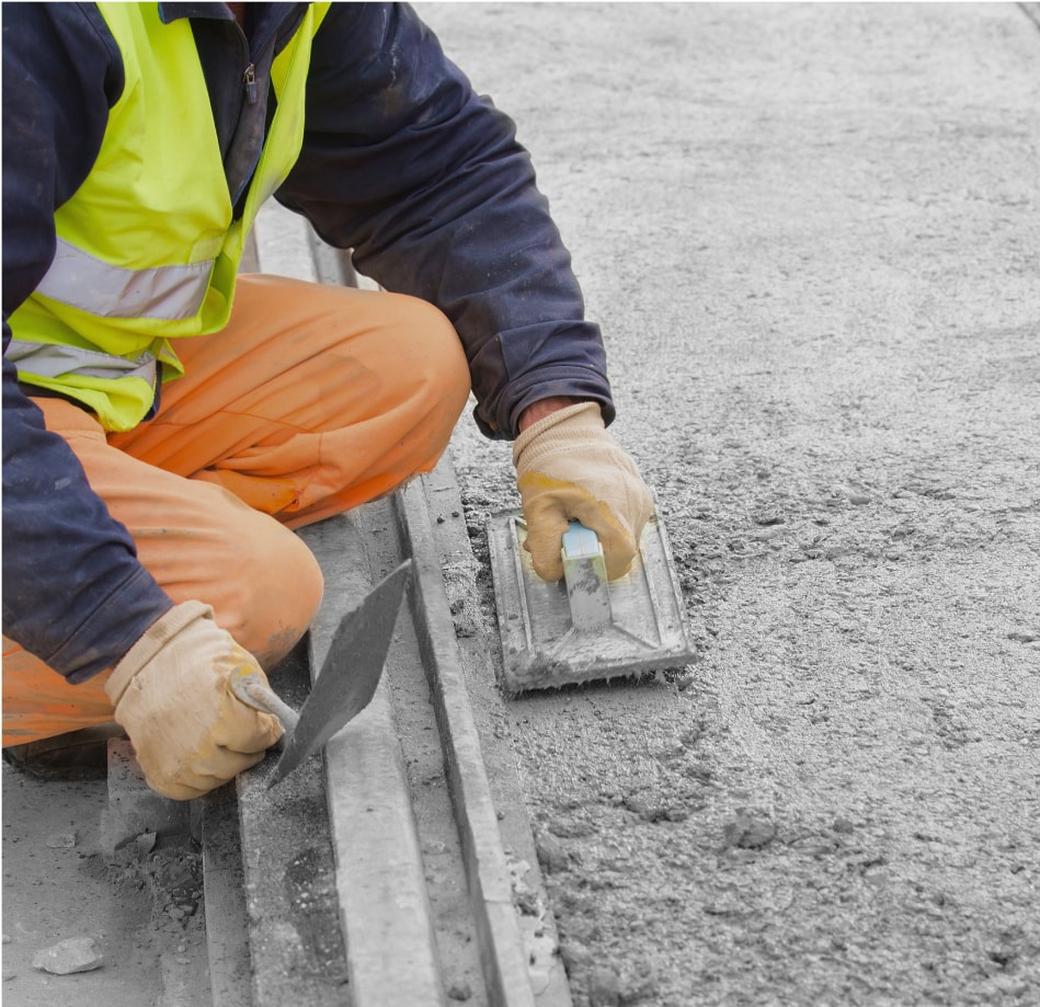 worker spreading wet concrete by hand