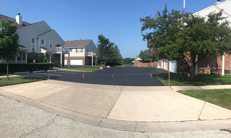 sidewalk and asphalt driveway in front of townhomes