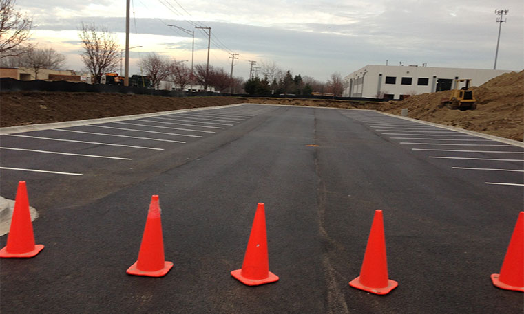 finished asphalt parking lot with construction cones