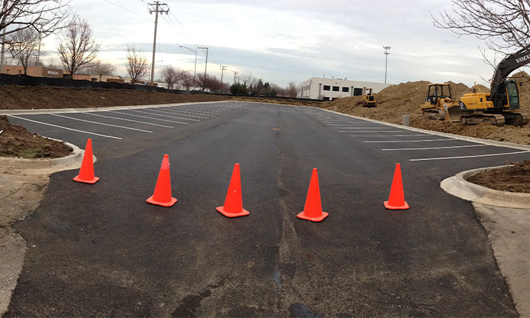 finished asphalt parking lot with construction cones