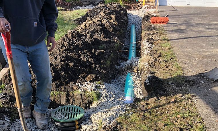 twin bros paving contractor in front lawn of home during drainage installation