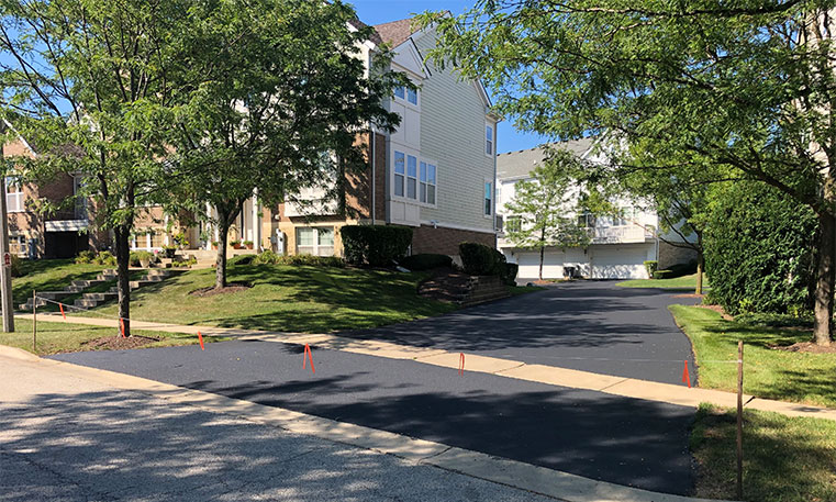 finished asphalt street and sidewalk in front of townhome association